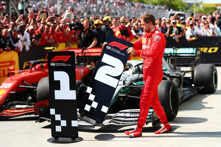 Second placed Sebastian Vettel of Germany and Ferrari swaps the number boards at parc ferme