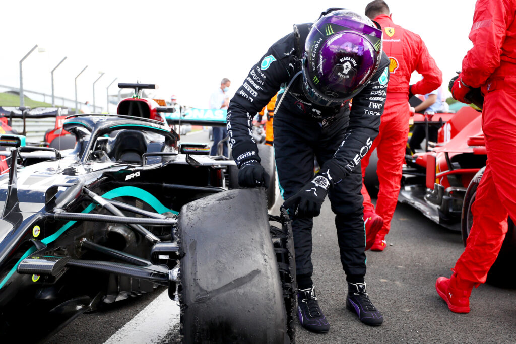 Lewis Hamilton inspects his Mercedes' punctured front-left tyre after winning the 2020 British Grand Prix.