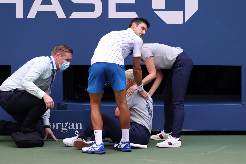 Novak Djokovic tends to a lineswoman after accidentally hitting her with a tennis ball during his fourth round US Open match in 2020.