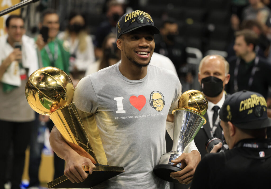 Giannis Antetokounmpo #34 of the Milwaukee Bucks holds the Bill Russell NBA Finals MVP Award and the Larry O'Brien Championship Trophy
