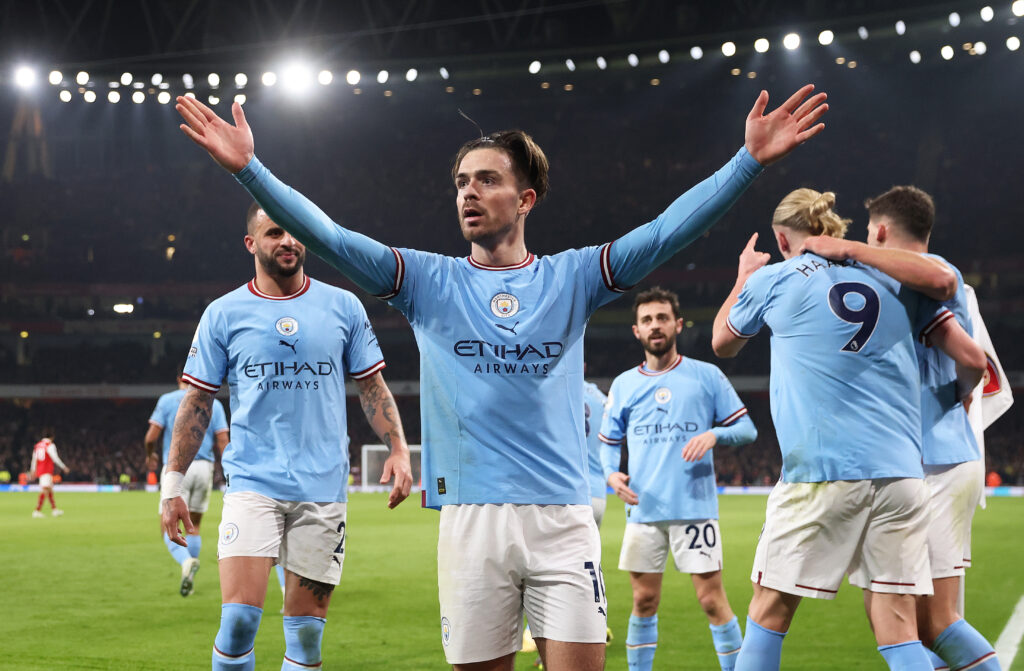 Jack Grealish celebrates scoring a crucial goal for Manchester City against Arsenal in a Premier League fixture at Emirates Stadium.