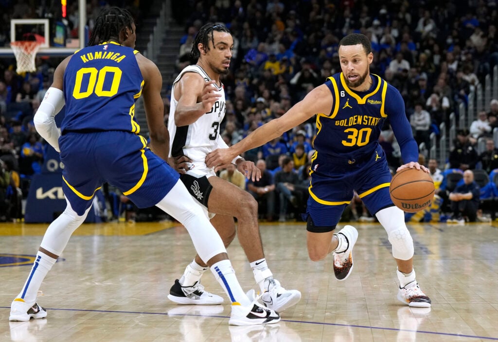 Stephen Curry #30 of the Golden State Warriors dribbles around a screen set by Jonathan Kuminga #00