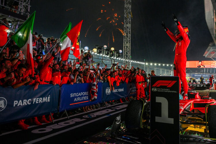 Carlos Sainz stands on Ferrari as he celebrates with team after winning the 2023 Singapore Grand Prix