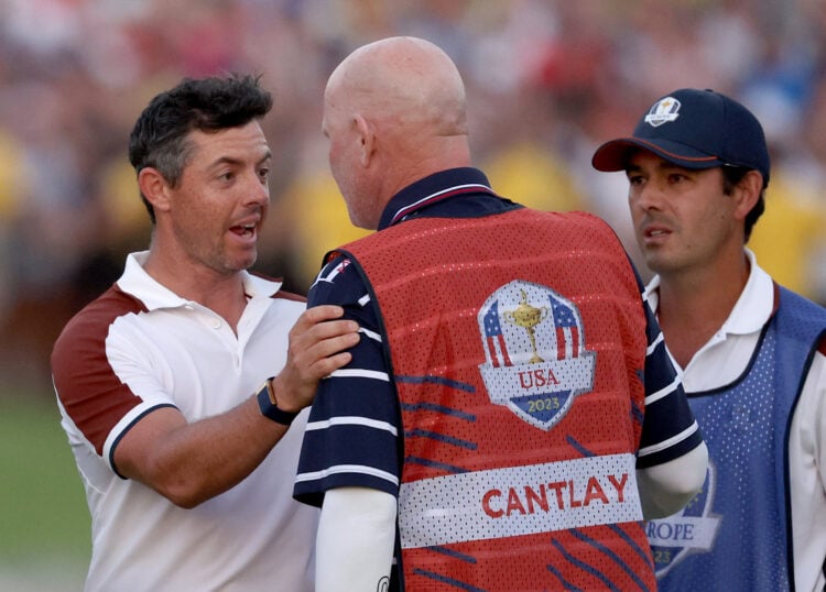 Rory McIlroy of Team Europe speaks with caddie of Patrick Cantlay of Team United States Joe LaCava