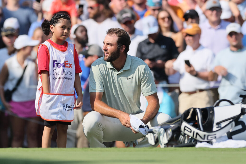 Scottie Scheffler of the United States talks to an honorary flag holder on the 18th green at the FedEx St Jude