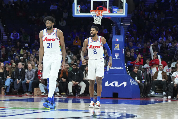 Joel Embiid #21 and Paul George #8 of the Philadelphia 76ers look on