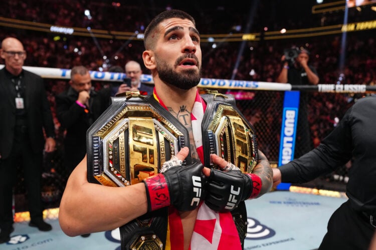 Ilia Topuria poses with two championships after his knockout win over Charles Oliveira at UFC 317