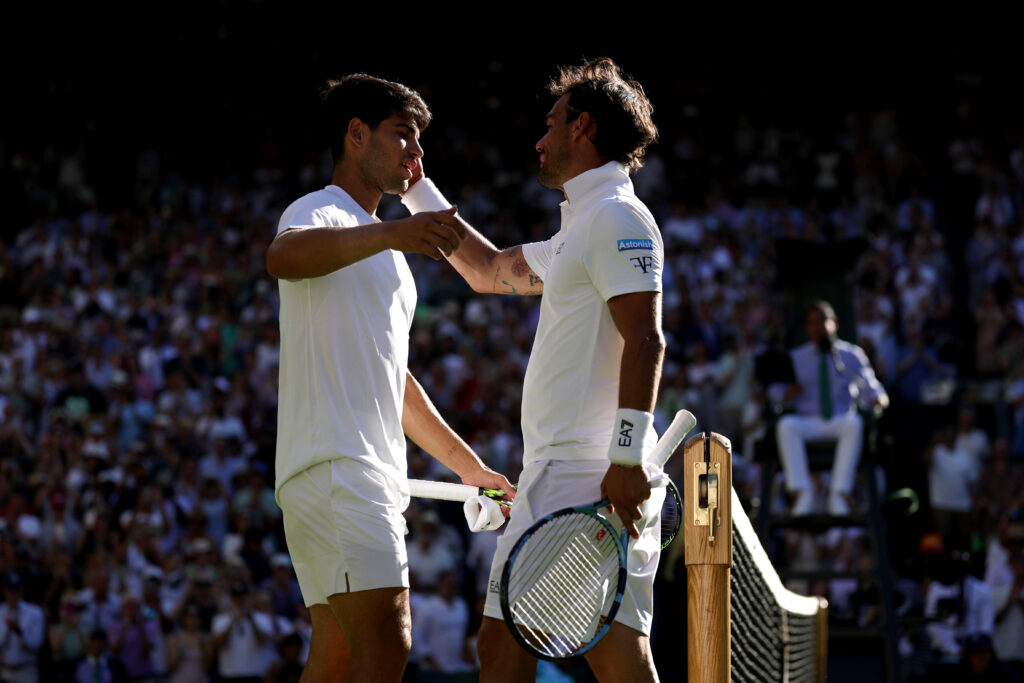 Carlos Alcaraz embraces Fabio Fognini at the net following his victory during the first round of Wimbledon 2025