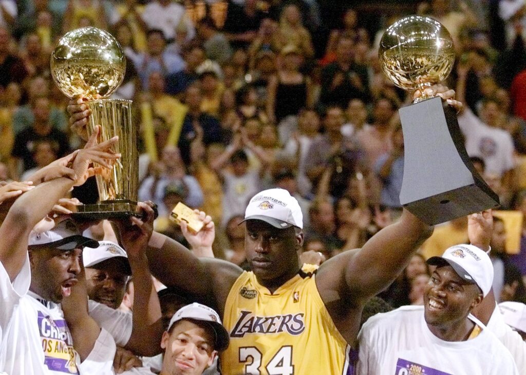 Shaquille O'Neal of the Los Angeles Lakers holds the MVP trophy and the Larry O'Brien Trophy for winning the NBA Championship in 2000.