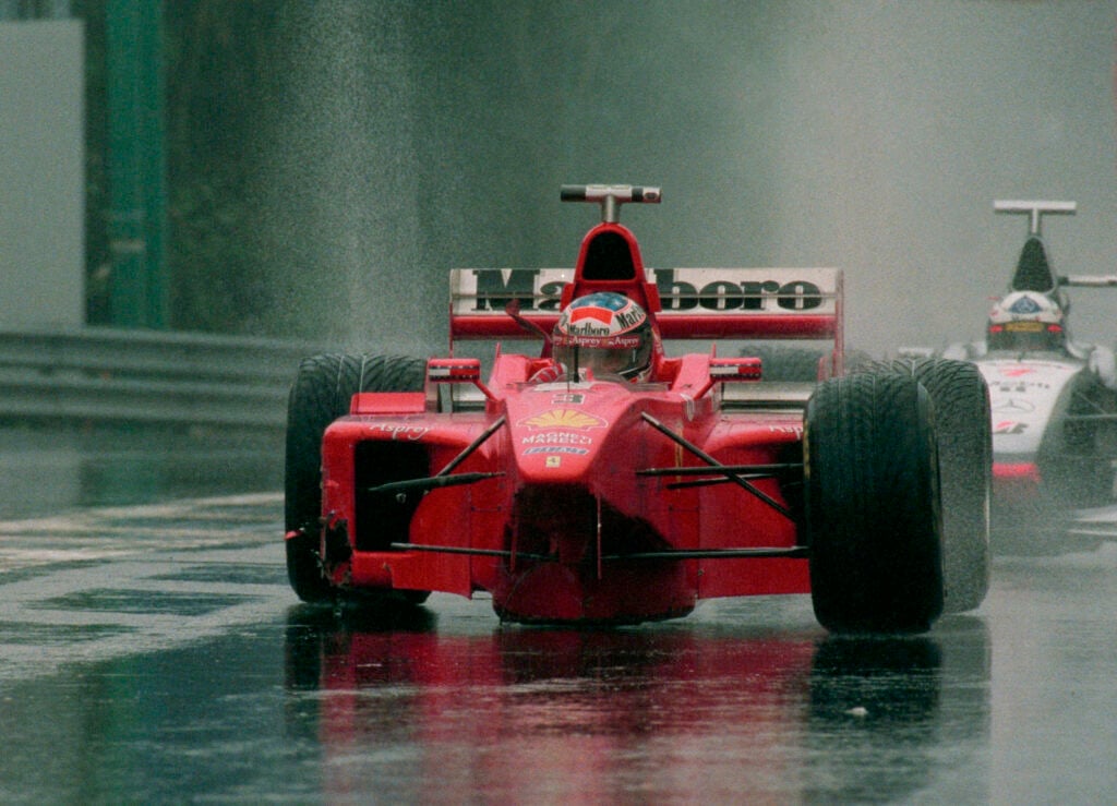 Michael Schumacher of Germany and Ferrari and David Coulthard of Scottland and McLaren Mercedes drive to the box after a crash