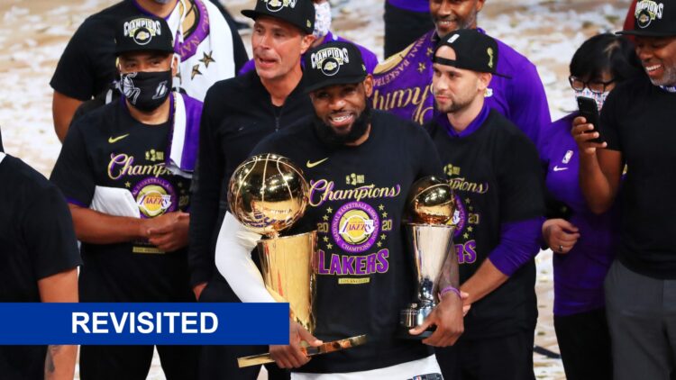 LeBron James #23 of the Los Angeles Lakers reacts with his MVP trophy and Finals trophy, and a revisited banner
